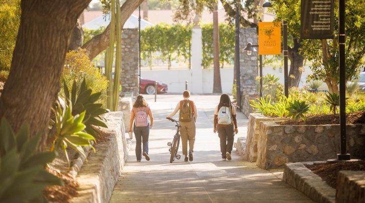 Three students walk side by side on Avery Walkway.